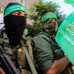 armed men in green headbands holding a green flag