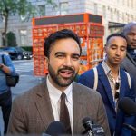 Mamdani’s Wife Exposed in Anti-Semitism Group Zohran Mamdani speaking to reporters on a city sidewalk