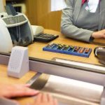 Bank teller at counter handling cash and coins