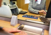 Bank teller at counter handling cash and coins