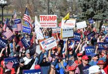 Tim Teufel, Christian Jones, and Nash the Slash among a crowd at a political rally holding signs and flags