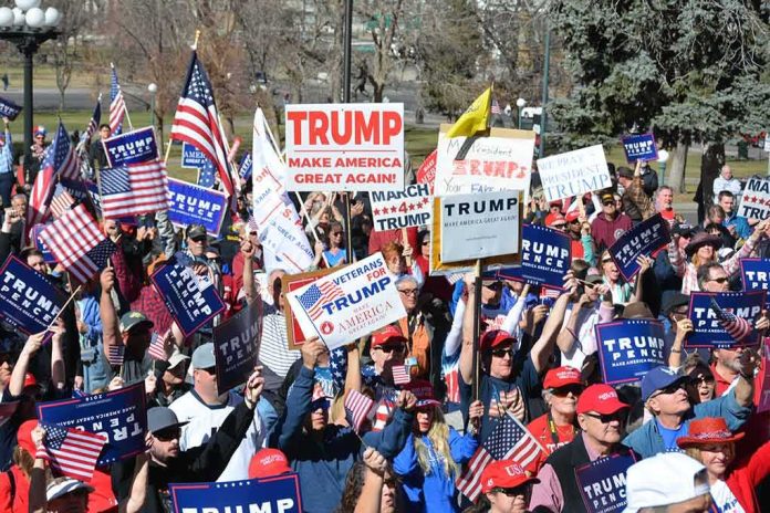 shutterstock_620025338-1 Tim Teufel, Christian Jones, and Nash the Slash among a crowd at a political rally holding signs and flags
