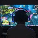 Beloved Influencer Kills Himself on Livestream Gamer wearing headphones facing a large screen